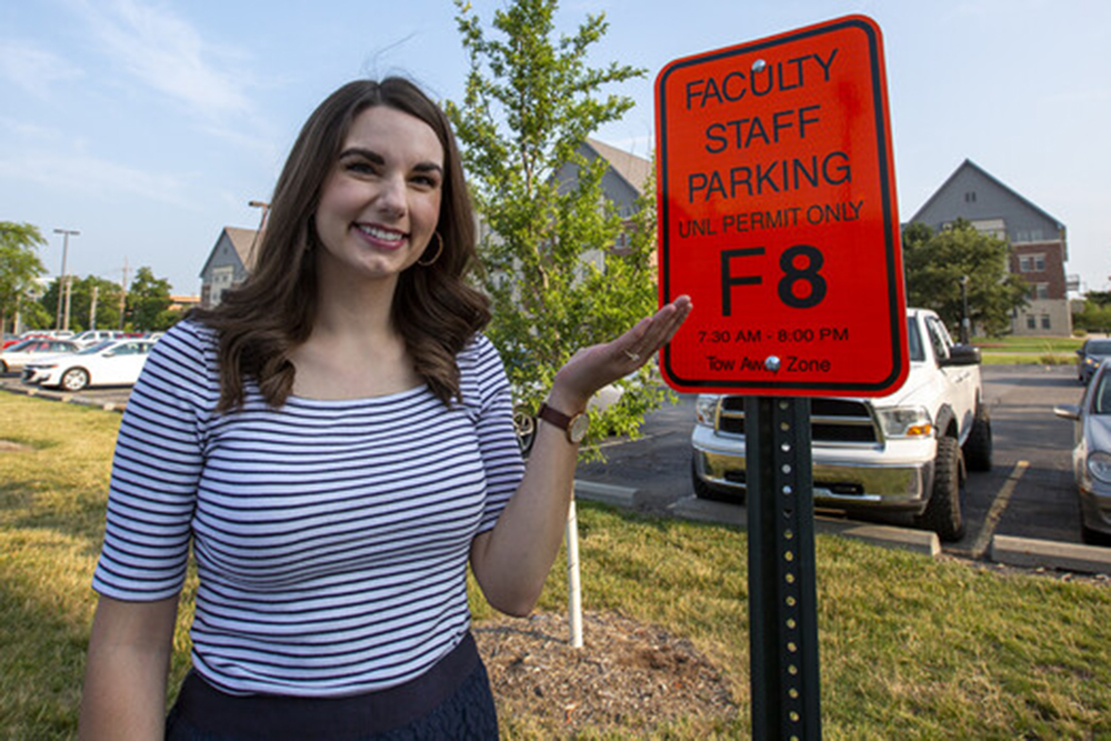 Bonnie Martin stands next to her reserved parking sign near Nebraska Hall. (University Communication)